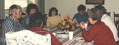 Family sitting at the table talking over things, with plenty of snacks on hand.